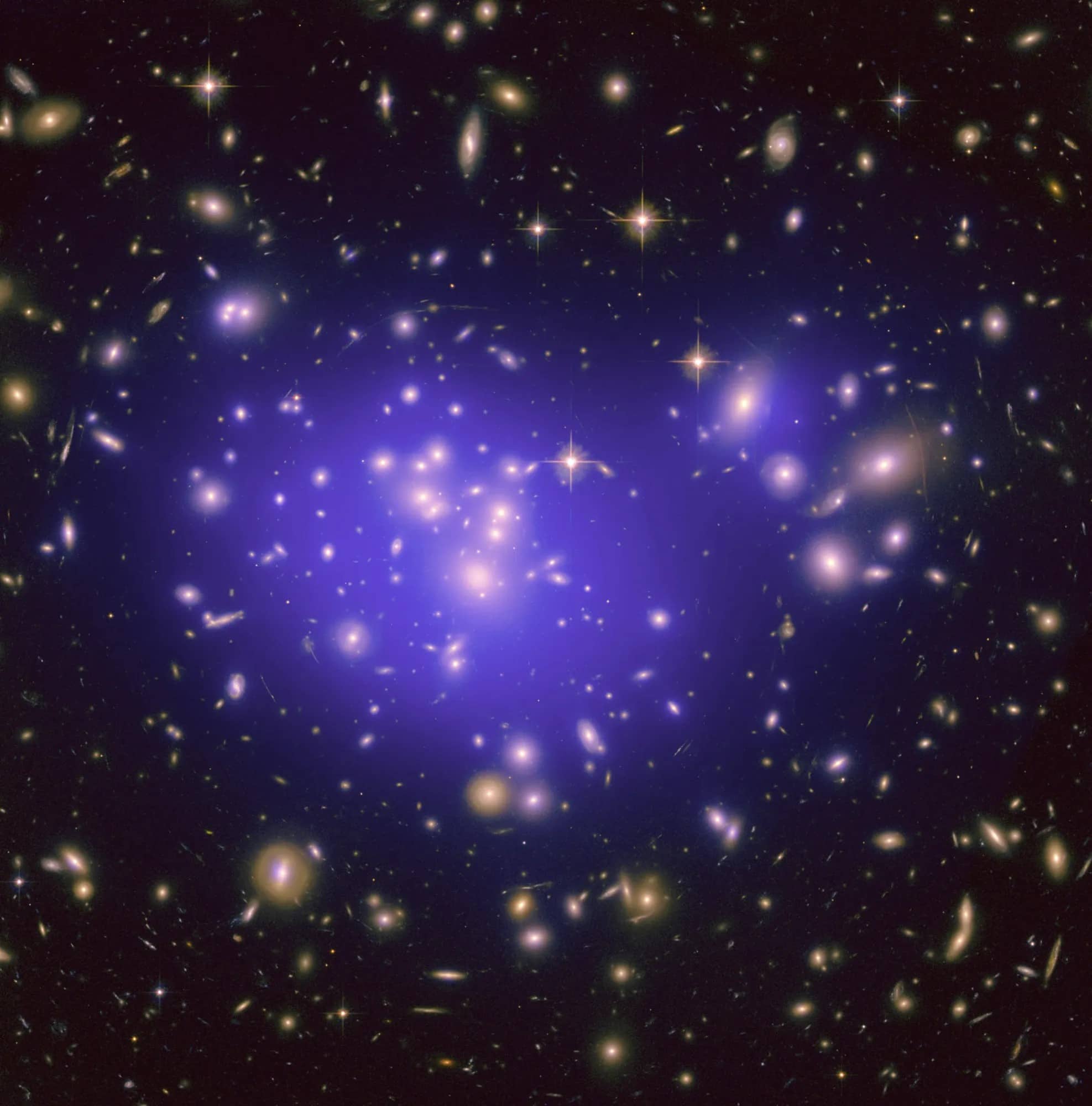 An image showing lots of galaxies against a black background, with a bluish-purple glow in the centre